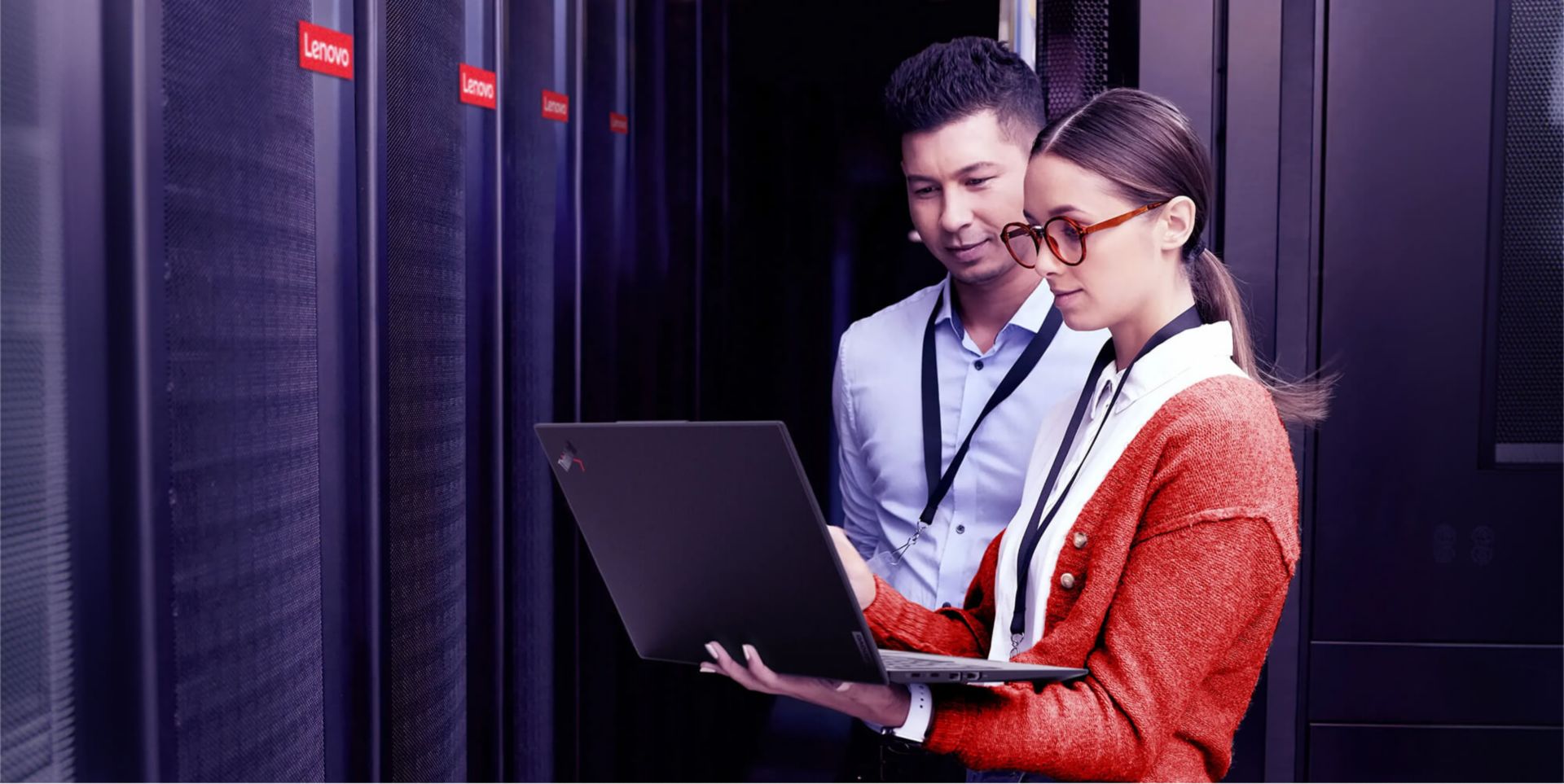 Two colleagues looking at a laptop in a server room.