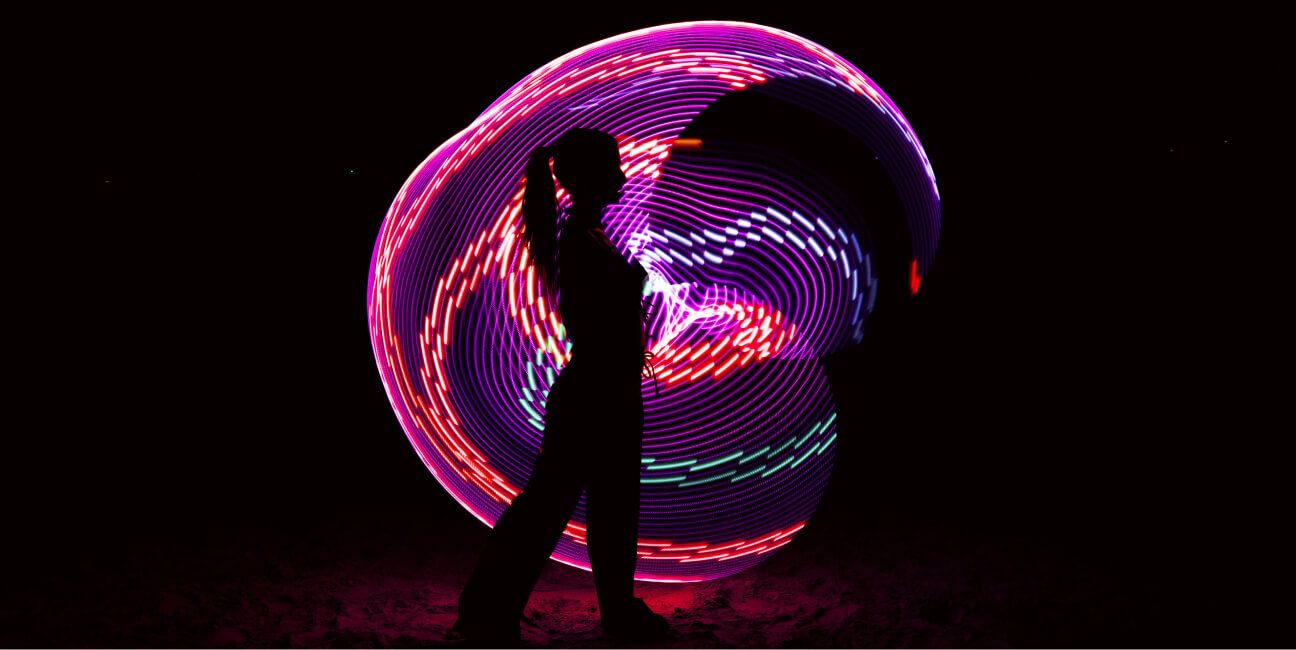 A woman silhouetted in front of a pink circle of light.