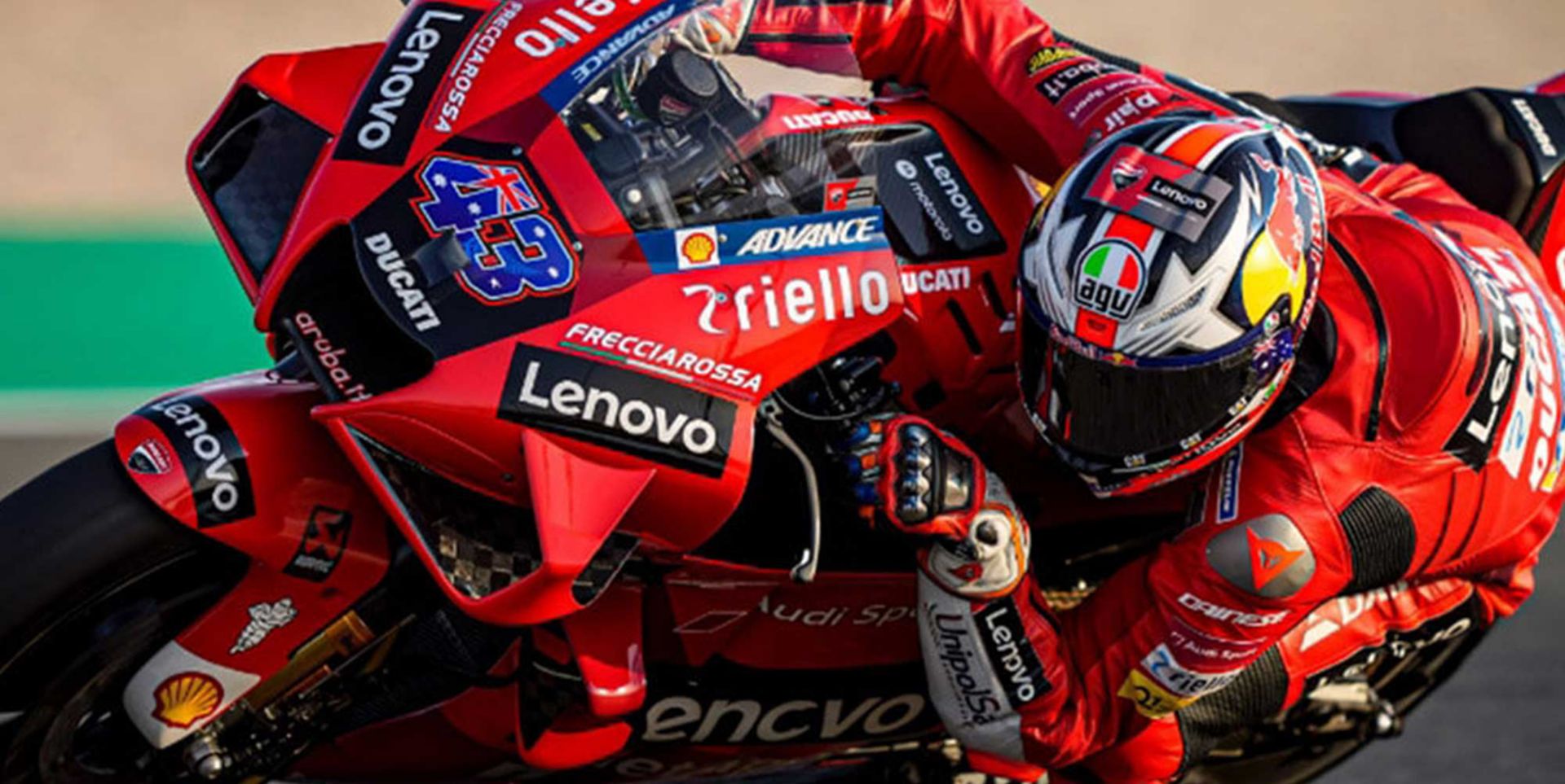 A motorcycle racer with Lenovo logos on his outfit leaning in for a turn.