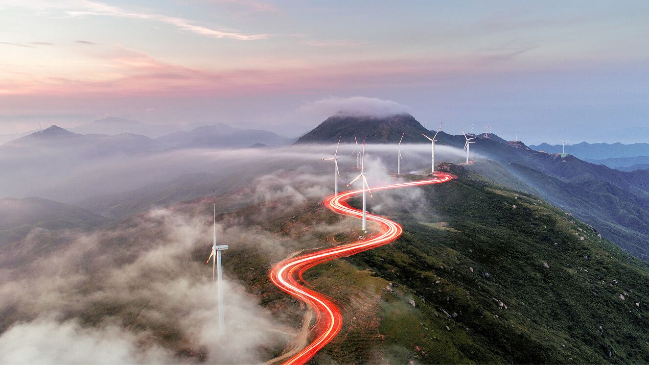 A squiggly red line along a hilltop road weaving between wind turbines.