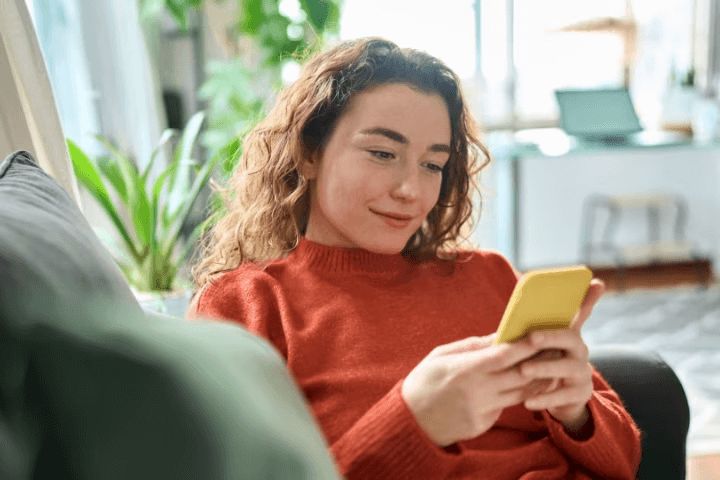 A woman in her house using a phone
