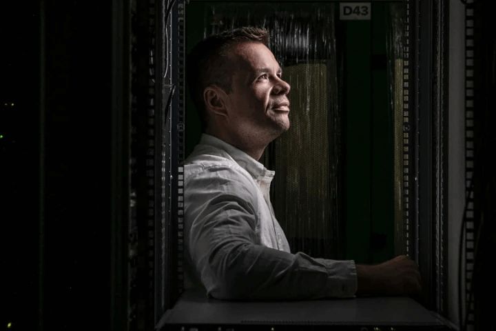 A man in a shaft of light looking up in a dark server room