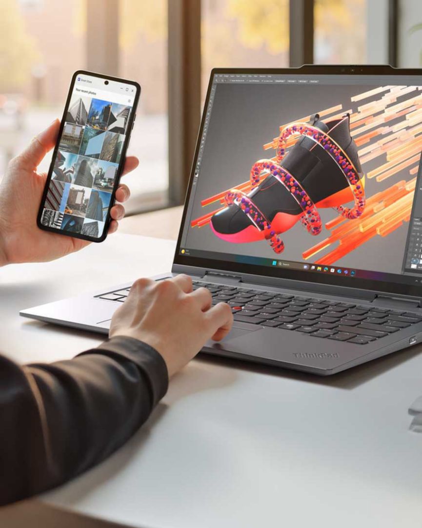 A person holding their phone and comparing the pictures to the content they’re creating on their laptop. 