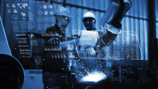 Two co-workers collaborating in manufacturing facility with charts overlaying screen in lights