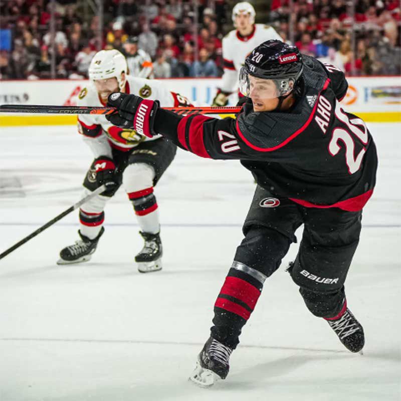 A Carolina Hurricanes player facing off on the ice against the Chicago Blackhawks.