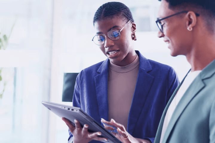 A woman holding a tablet and having a conversation with a colleague
