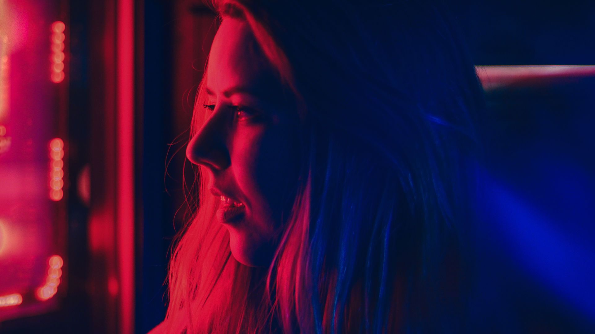 A woman’s face washed in red light. 