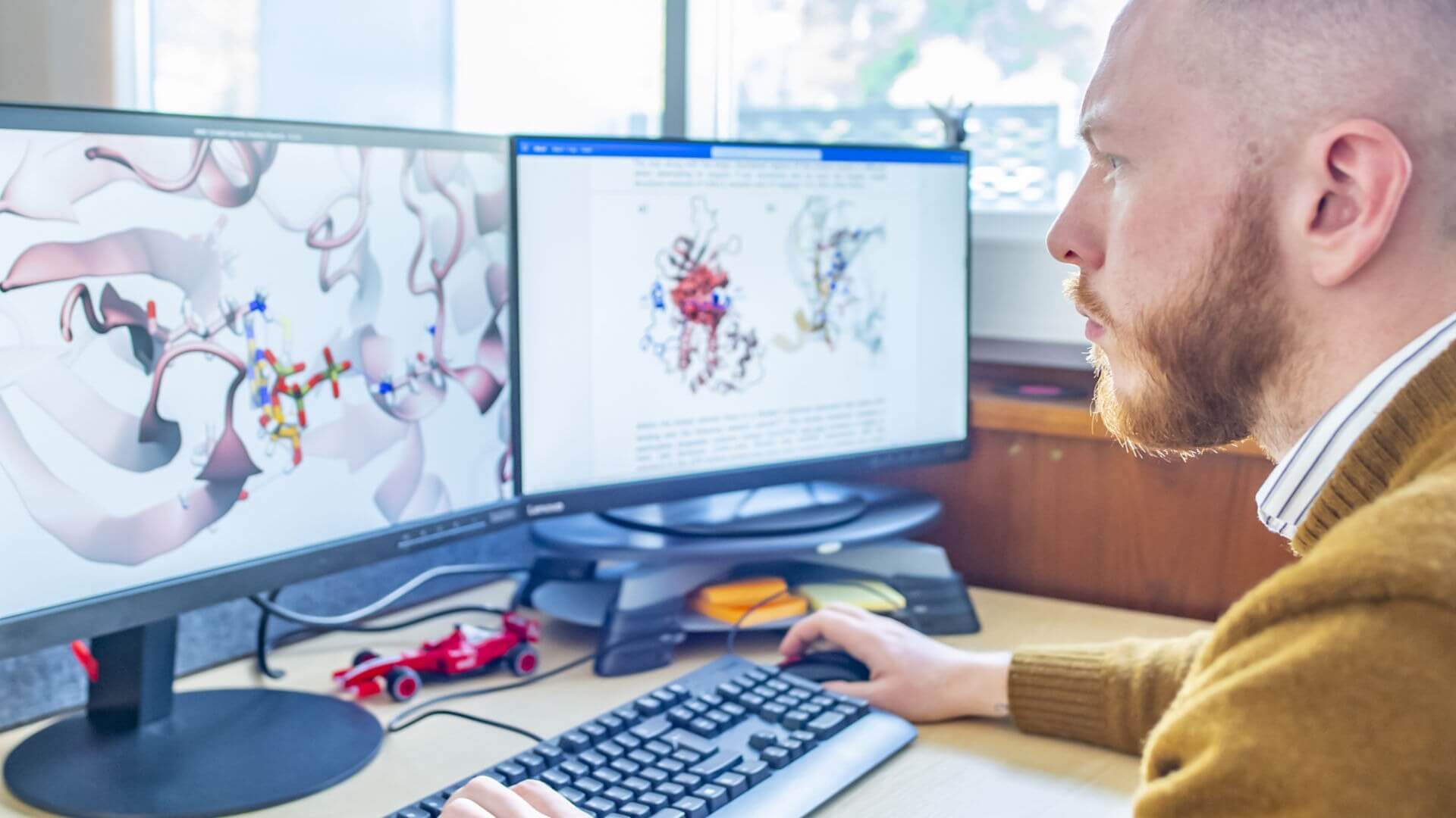A student using two computer screens to conduct scientific research. 