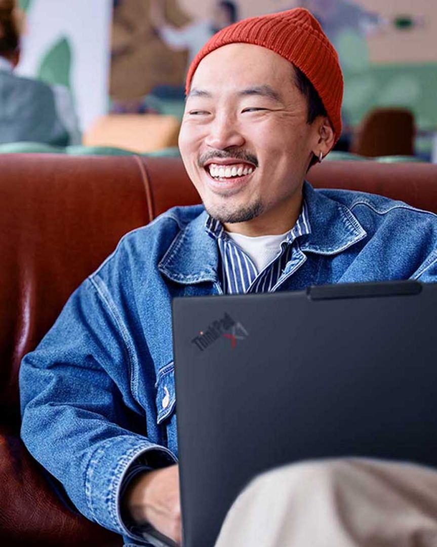 A man smiling while using his ThinkPad at a coffee shop.