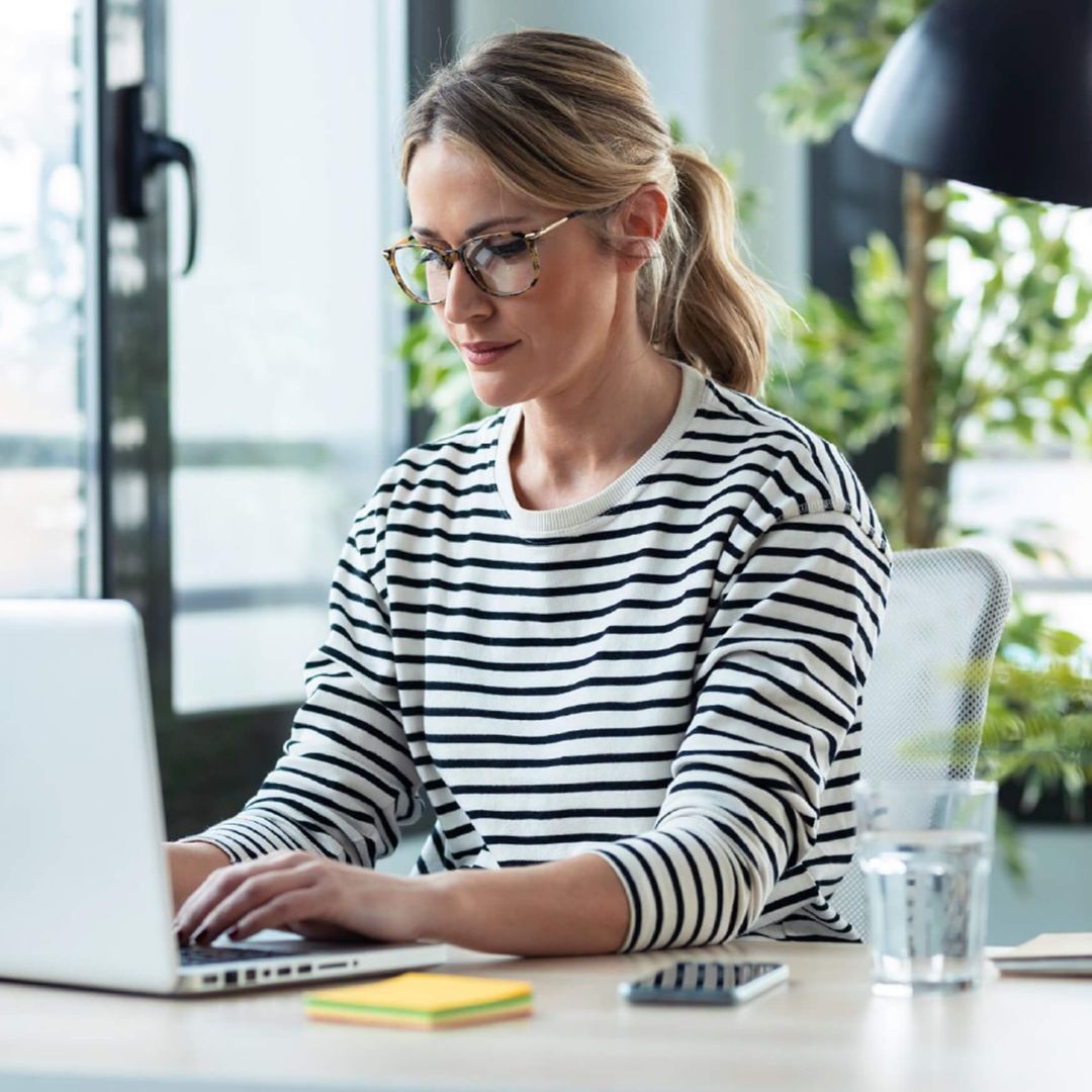 A woman typing on her laptop at a desk.