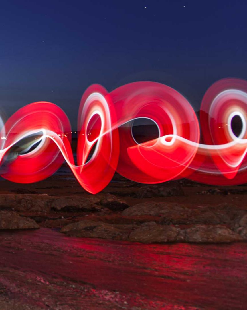 Boucles de lumière rouge devant un ciel nocturne.