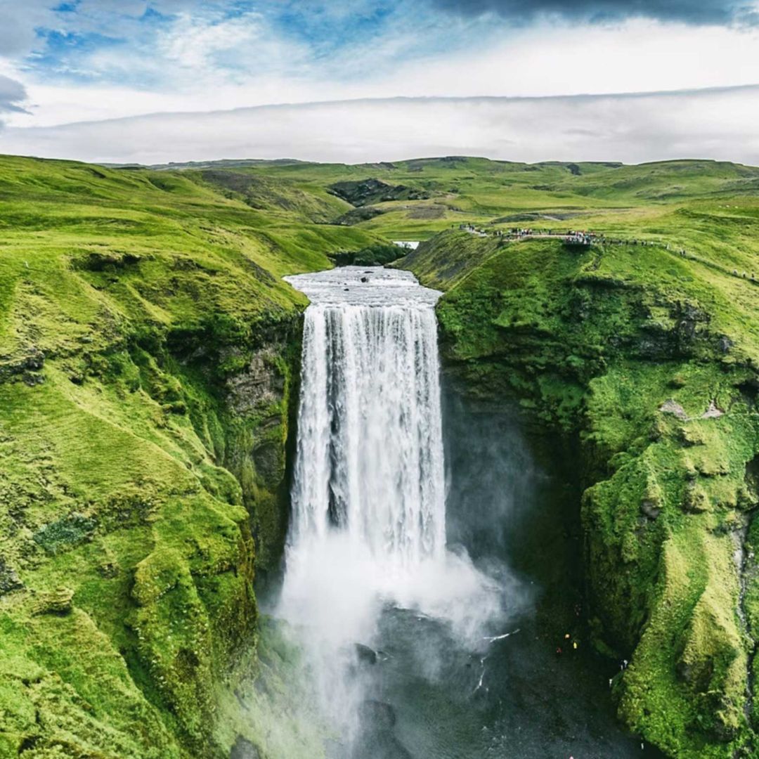 A large waterfall cascading down between lush green terrain.