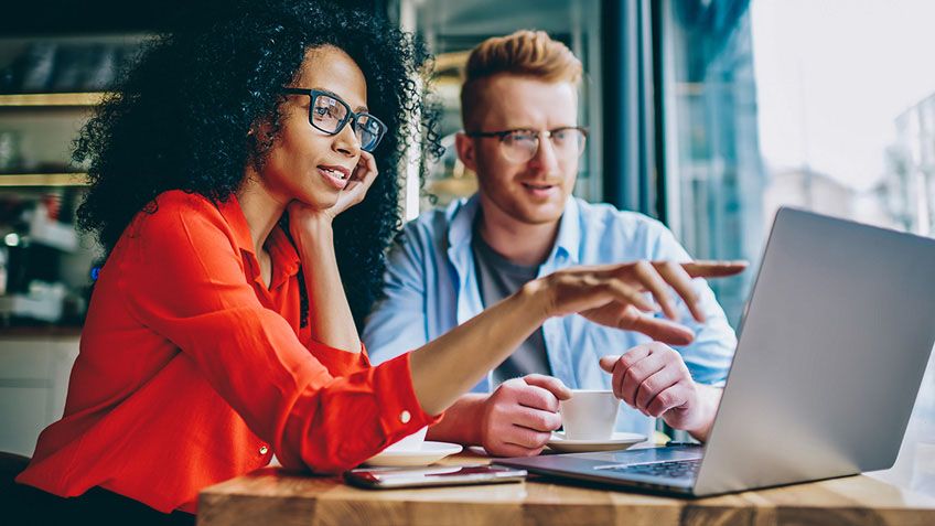 Two co-workers collaborating using a laptop