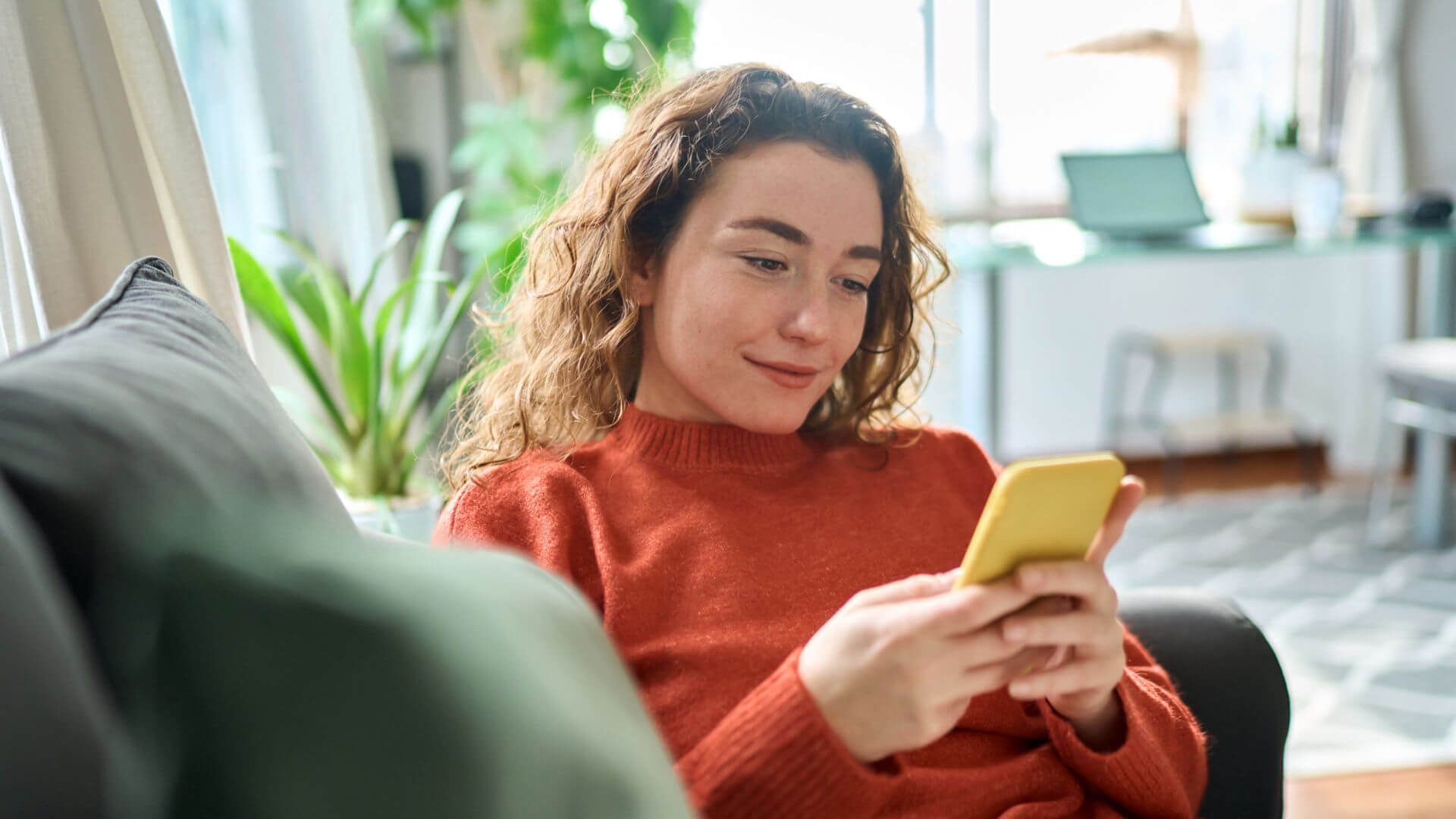 A woman scrolling on her phone on a couch. 