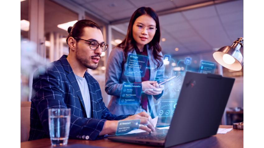 Two people collaborate for work at a desk with illustration of a holographic display emerging from a Lenovo laptop.