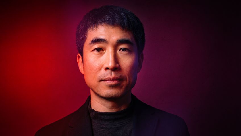 Portrait of a man with dramatic red and purple lighting.