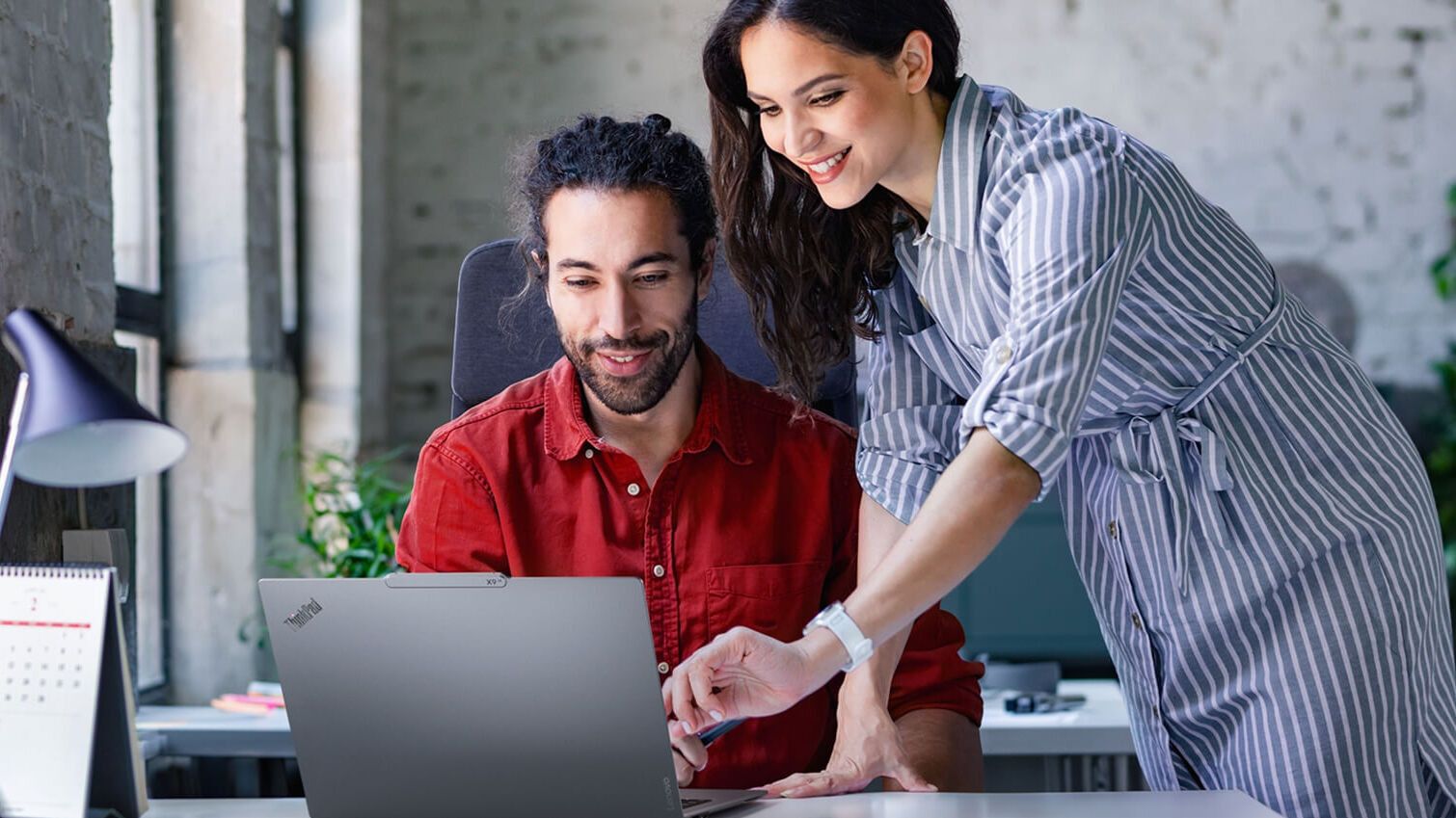 Una colega que le muestra a su colega masculino algo en su laptop.