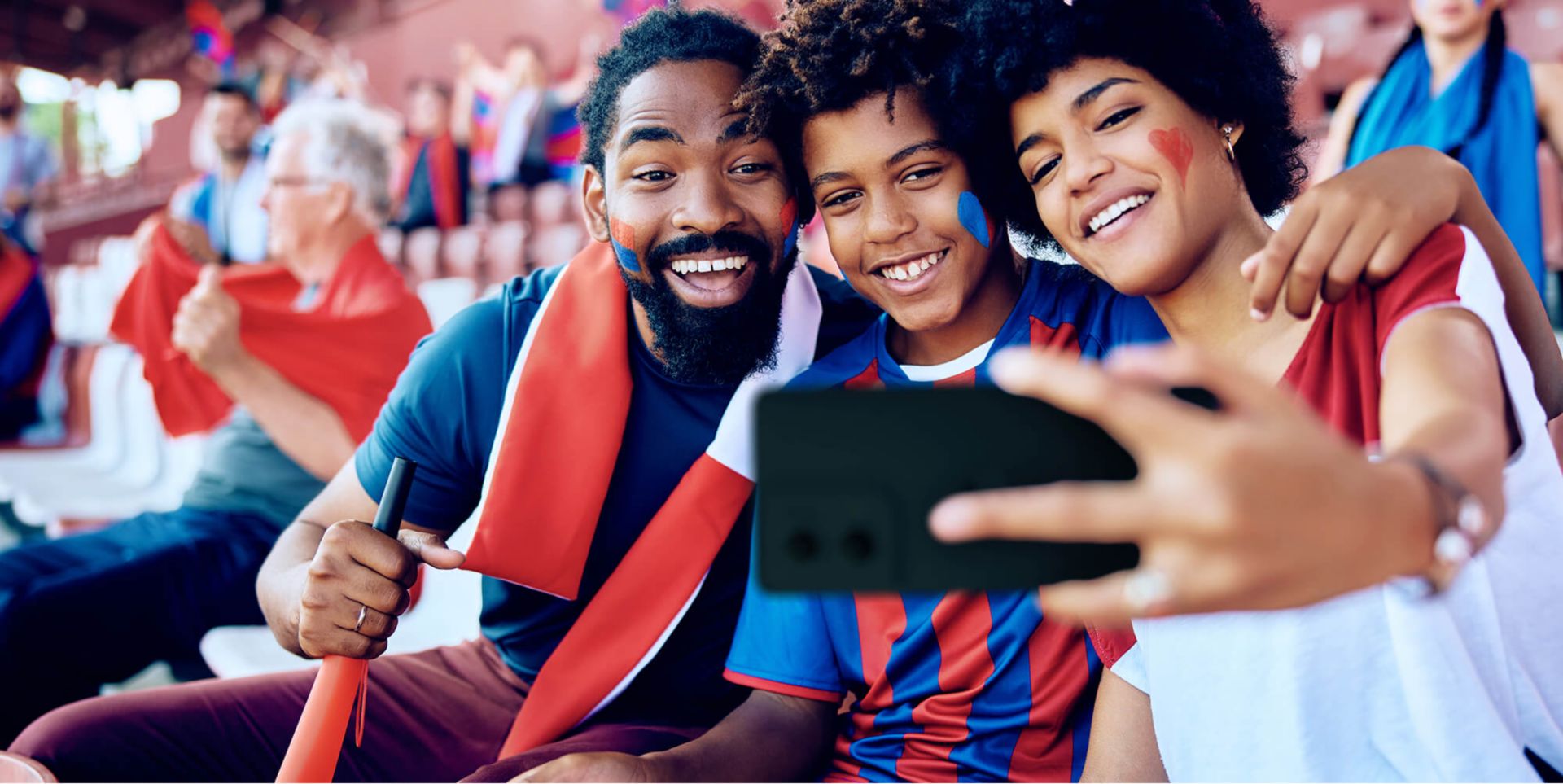Parents and their son taking a selfie in the stands of a game.