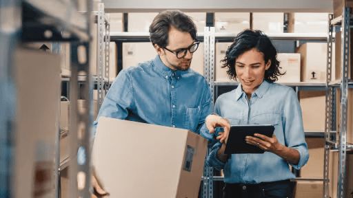 Two colleagues looking at an tablet while one holds a box
