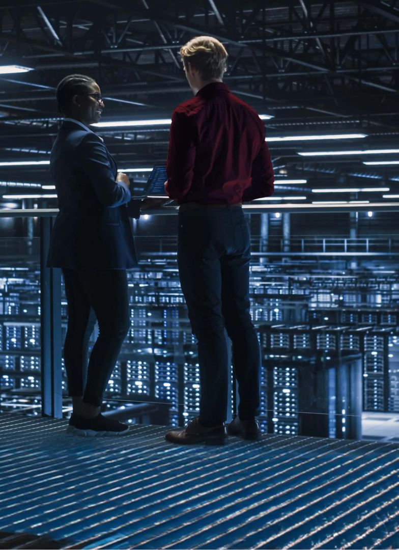 Two colleagues overlooking a giant server room.