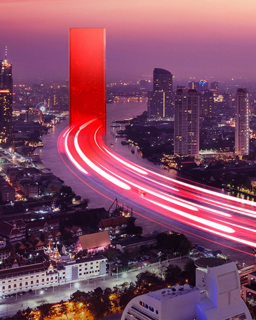 A timelapse of cars using the highway to enter a city with the red Lenovo portal in the middle of the road. 
