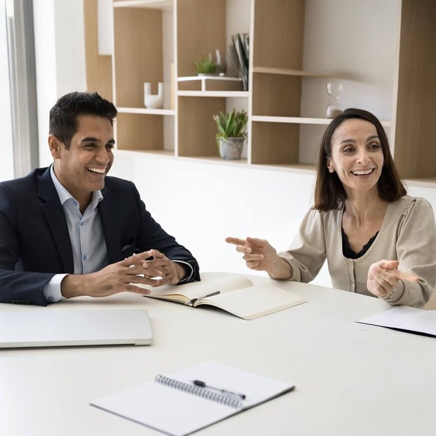 Two colleagues smiling in a conference room.