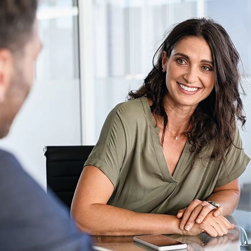 A woman smiling at a conference table.