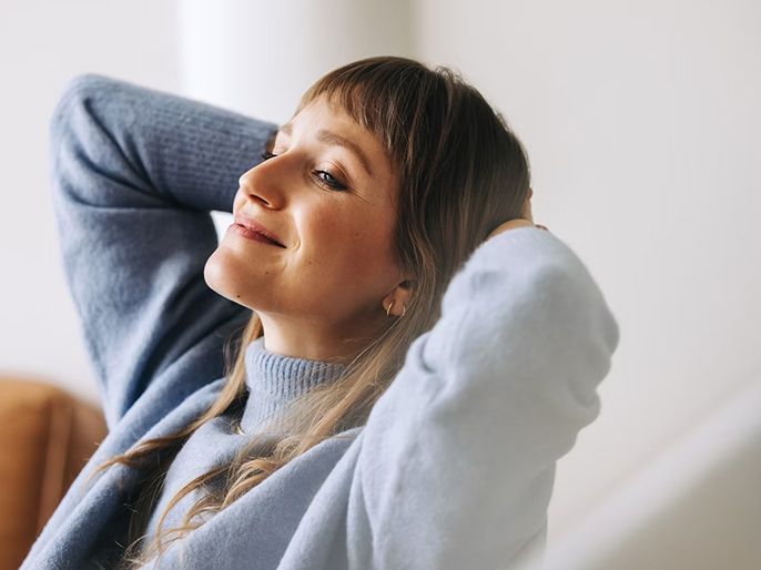 A woman relaxing with her hands behind her head.