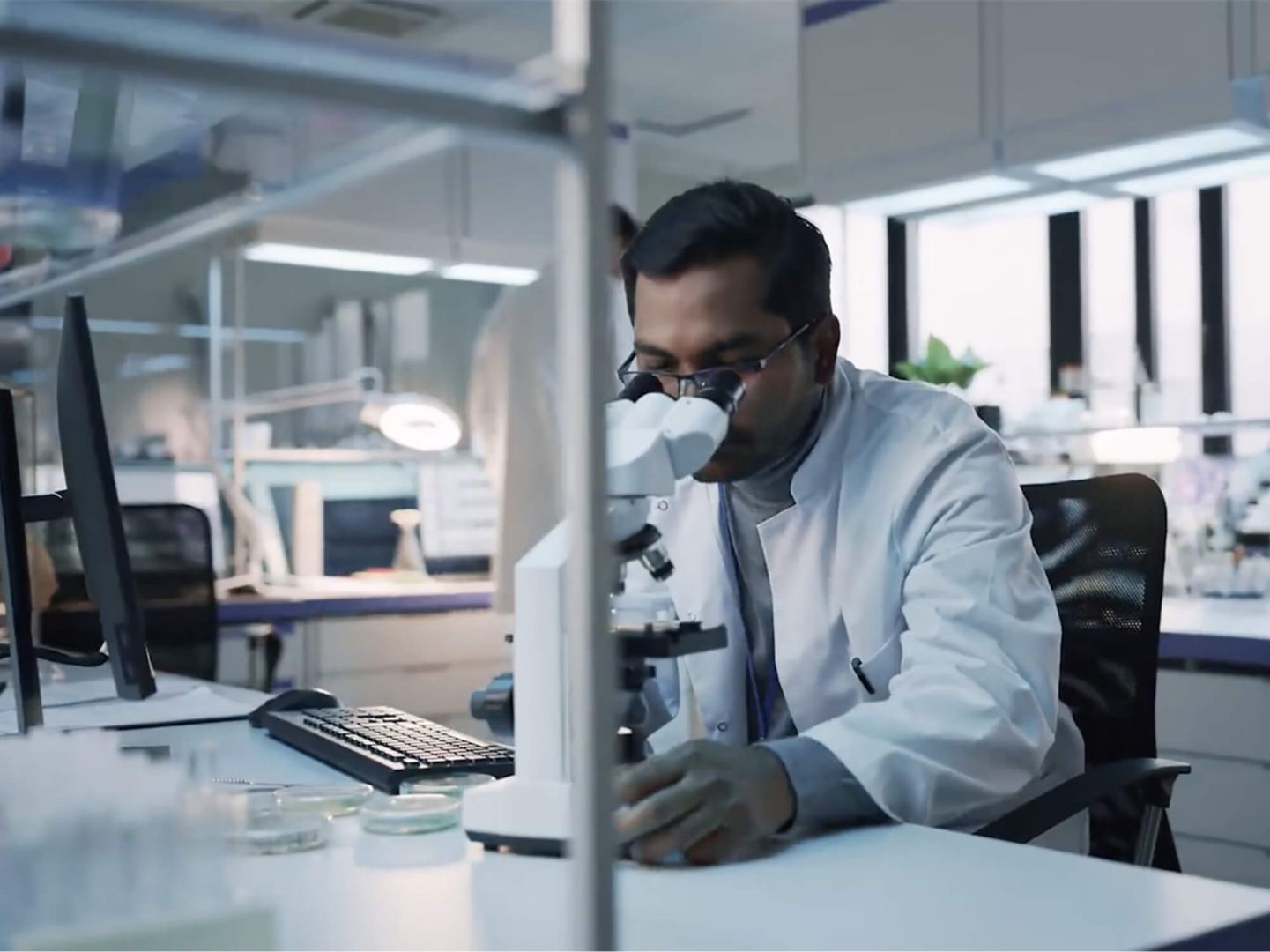 A scientist using a microscope in a lab.