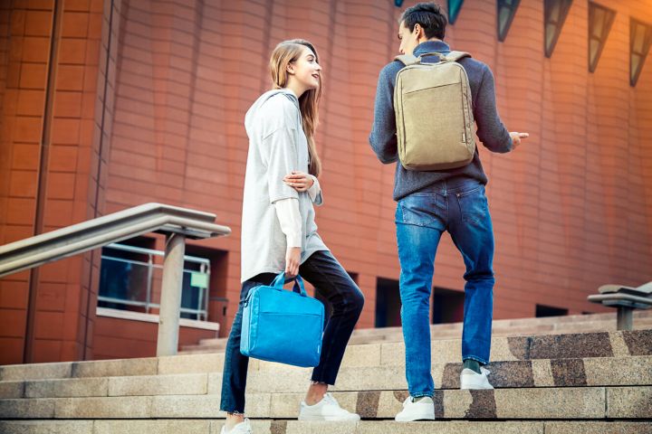 Two students ascending outdoor stairs and wearing Lenovo backpacks.