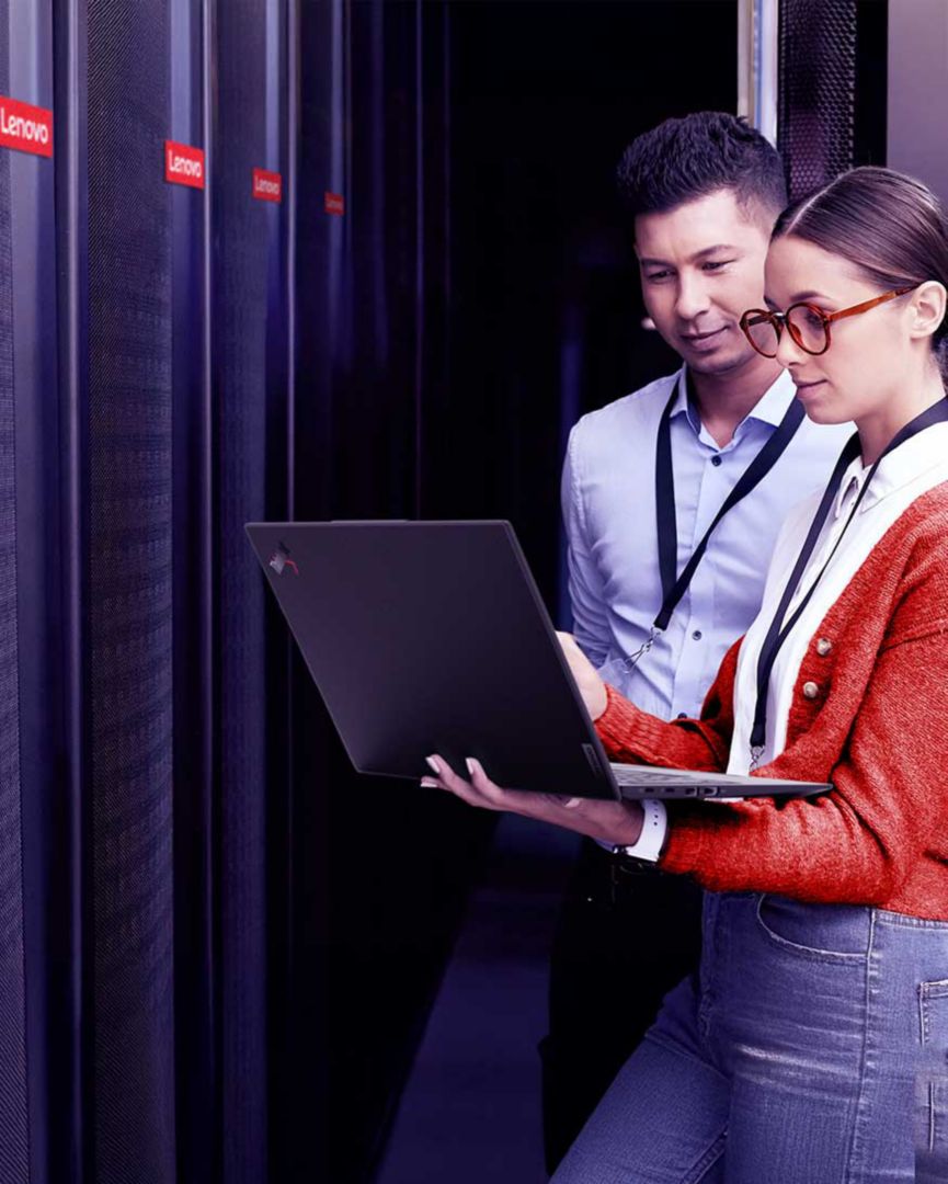 Two colleagues looking at a laptop in a server room. 