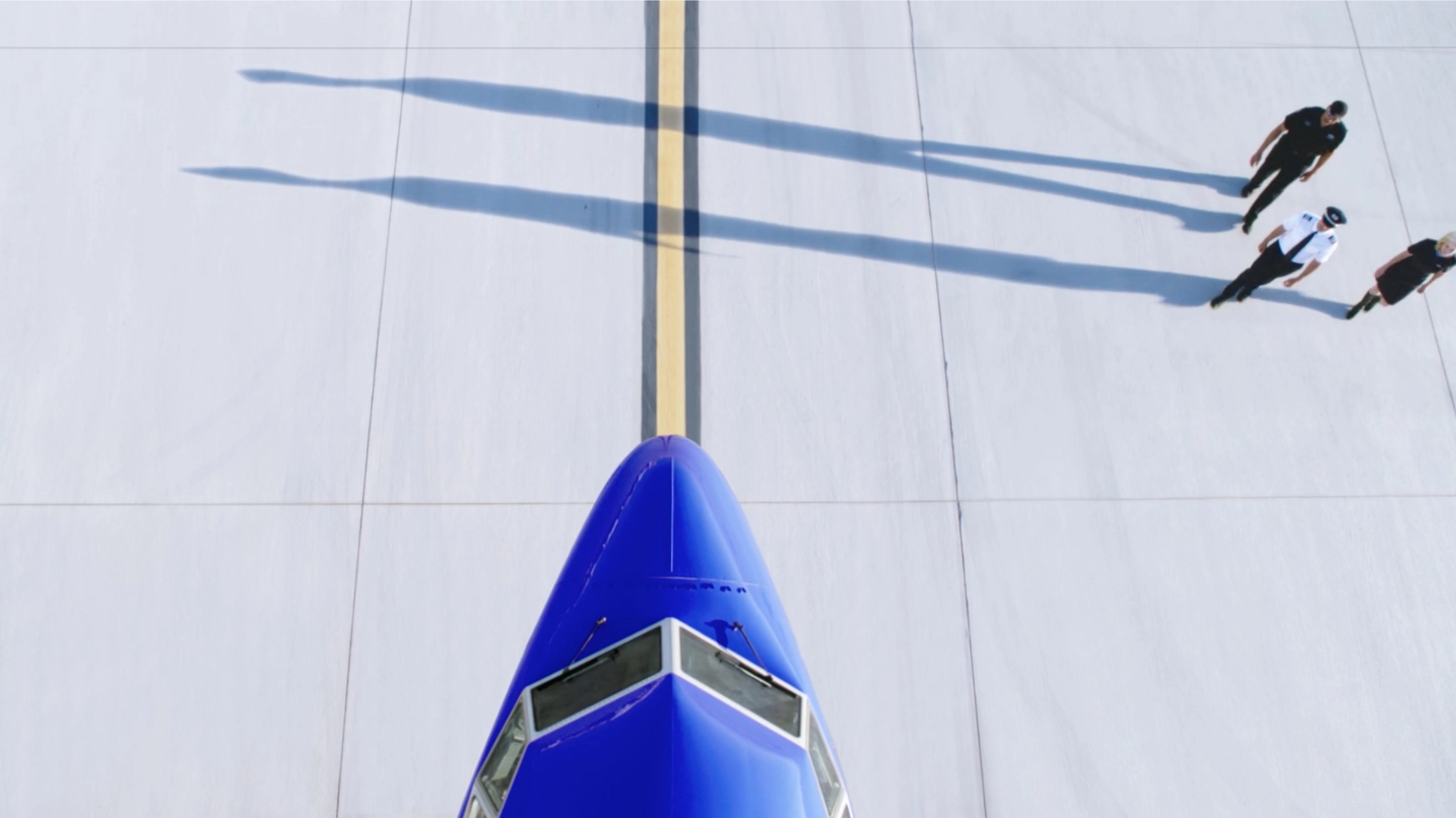 nose of southwest airplane with pilot and flight attendants walking towards plane