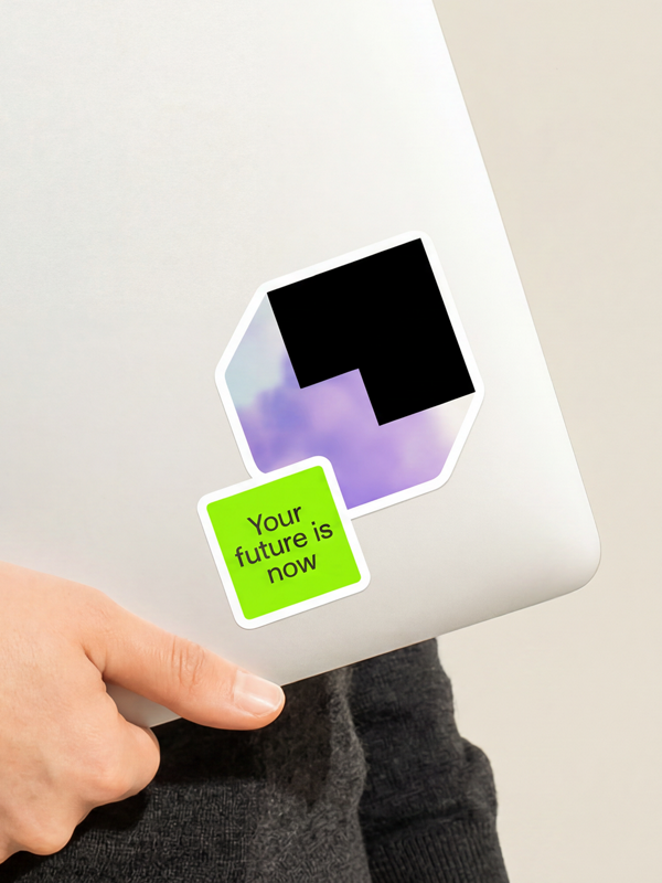 Tenarai logo sticker and bright green “Your future is now” sticker on a silver laptop.