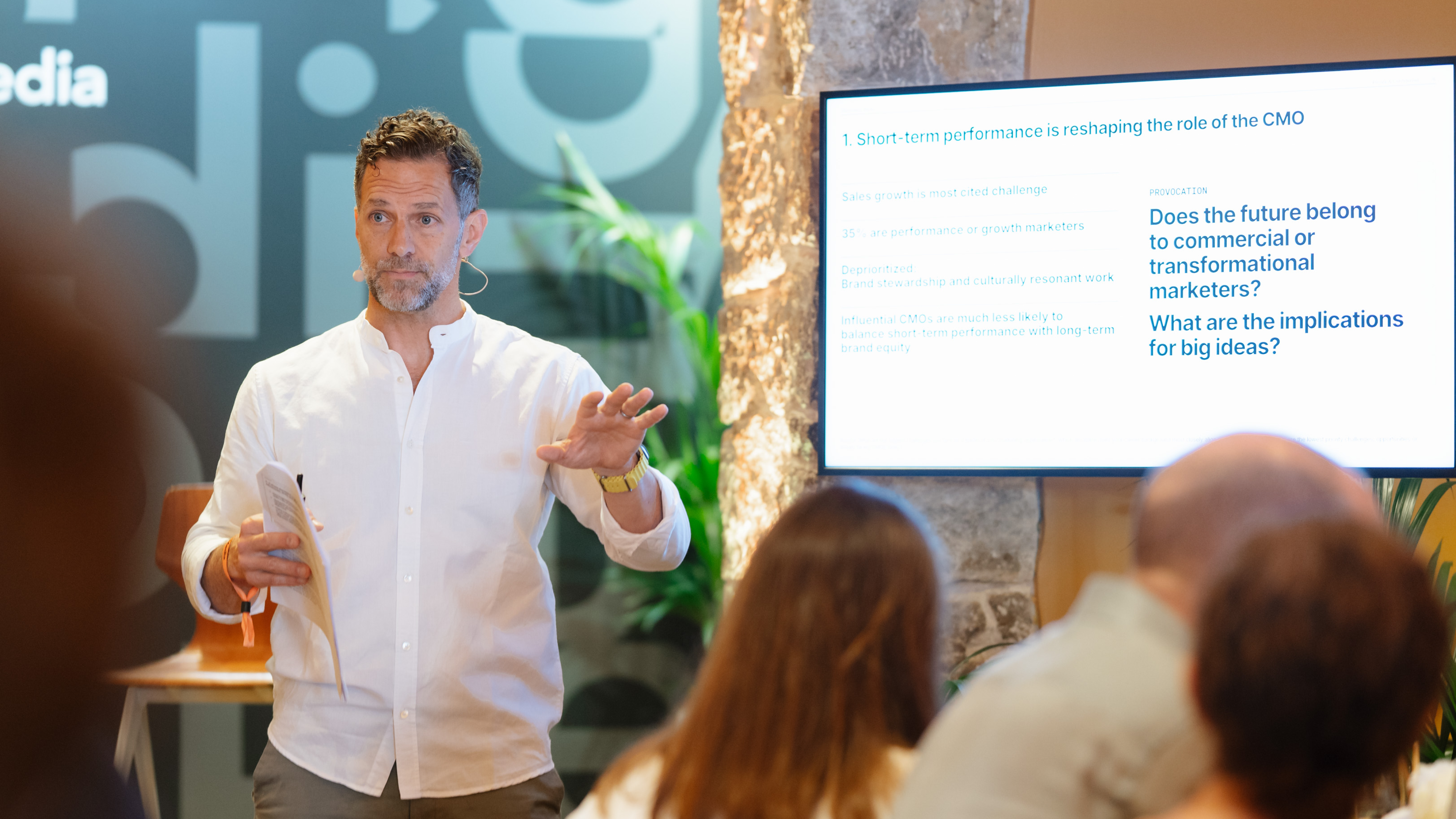White man standing in front of a screen presenting to an audience