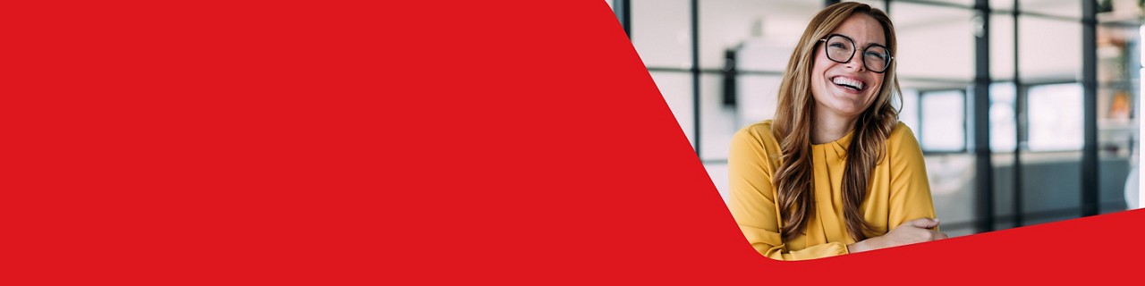 Photo d’une courtière d’assurance, dans son bureau, heureuse de pouvoir profiter des solutions de la Banque Nationale