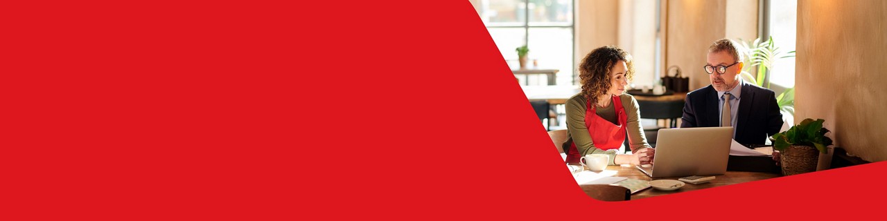 Photo d’une propriétaire de café et son directeur de comptes de la Banque Nationale discutant de financement bancaire pour son entreprise devant un ordinateur portable 