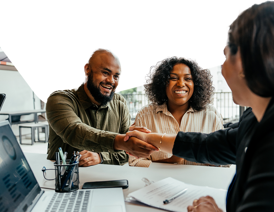 Photo of a couple shaking hands with an advisor at one of National Bank’s international offices 