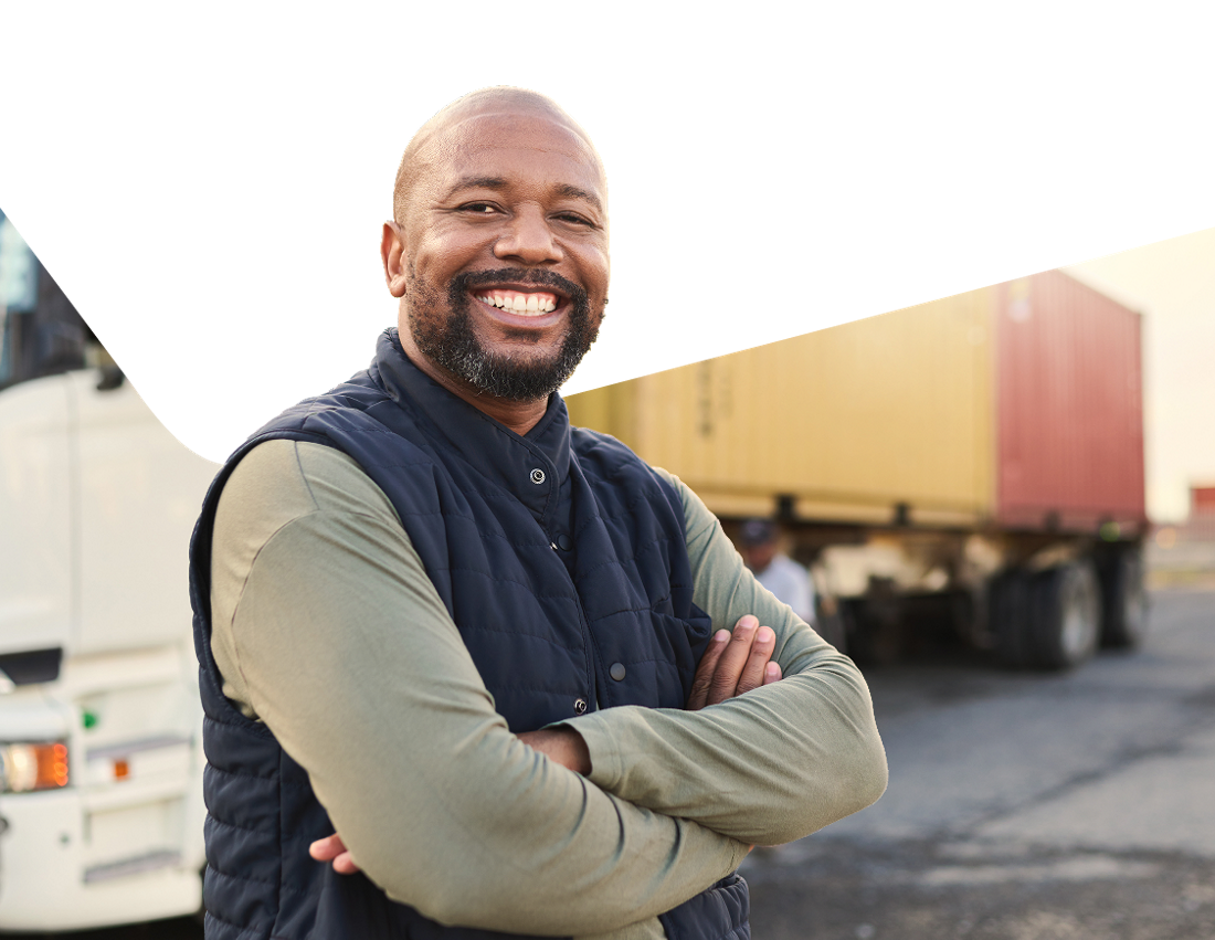 Photo d’un homme qui sourit devant son camion avec lequel il fait du commerce transfrontalier 
