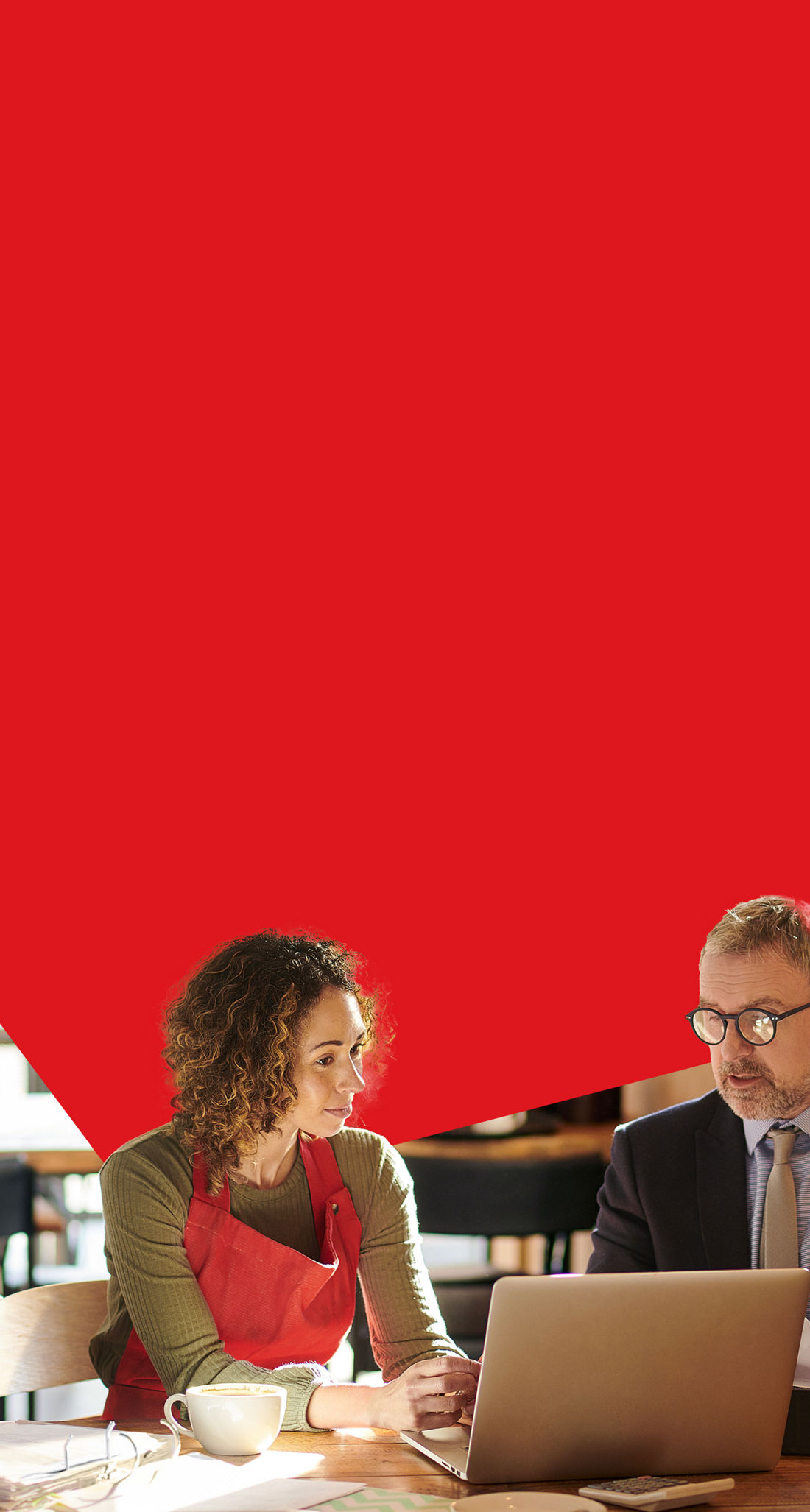 Photo d’une propriétaire de café et son directeur de comptes de la Banque Nationale discutant de financement bancaire pour son entreprise devant un ordinateur portable 