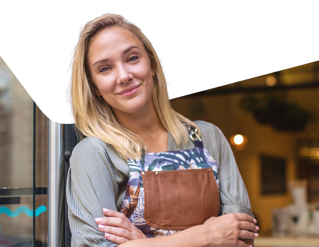 Photo of an entrepreneur standing in front of their business smiling as she enjoys the advantages of the National Bank Business Line Mastercard credit card