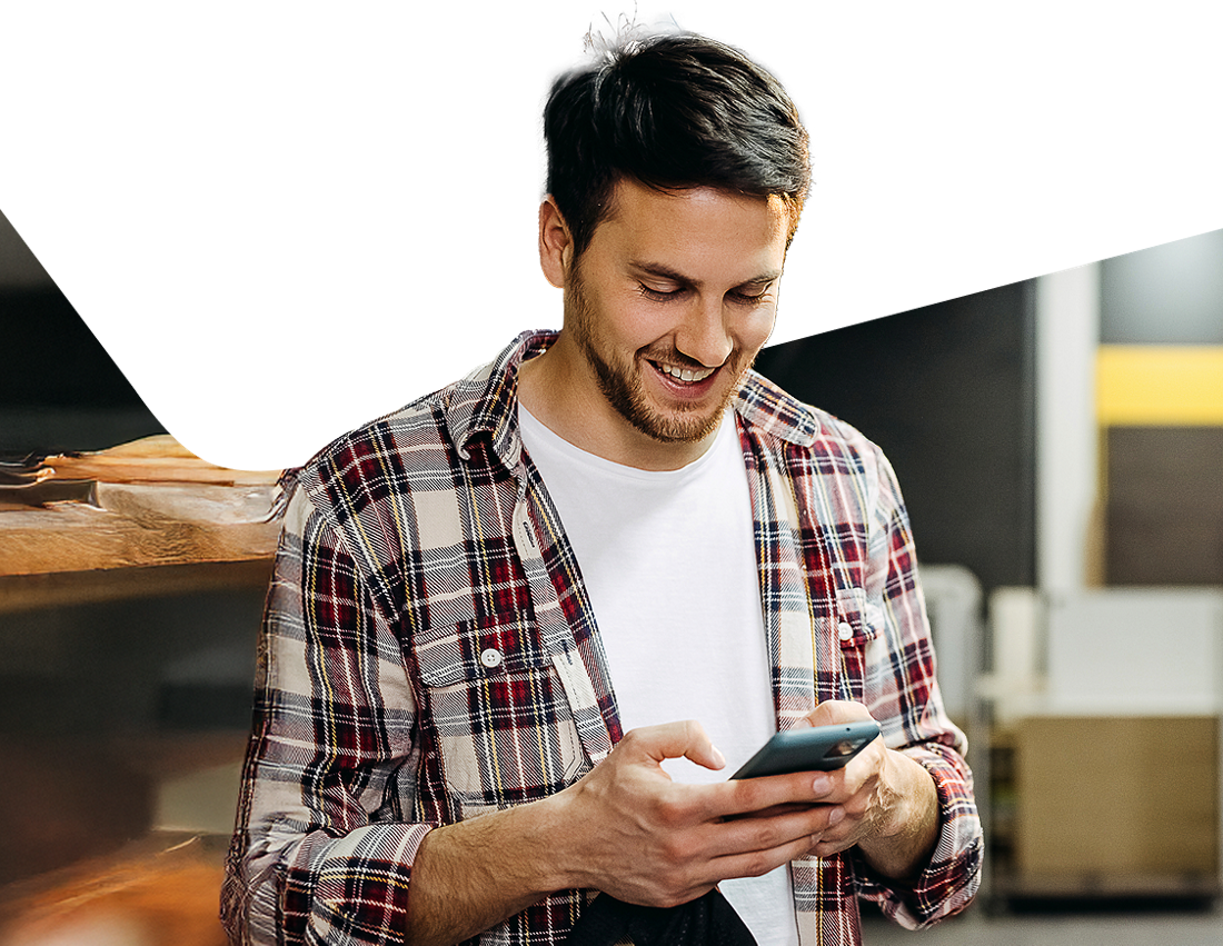 Photo of an entrepreneur in their shop opening an account with the National Bank Digital Business Package on their cell phone