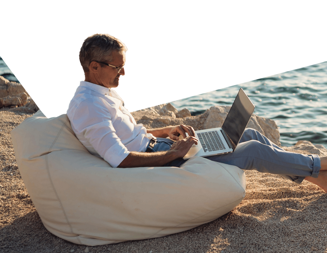 Photo d’un homme à la plage, en Floride, consultant les services en ligne pour particuliers de Natbank sur son ordinateur