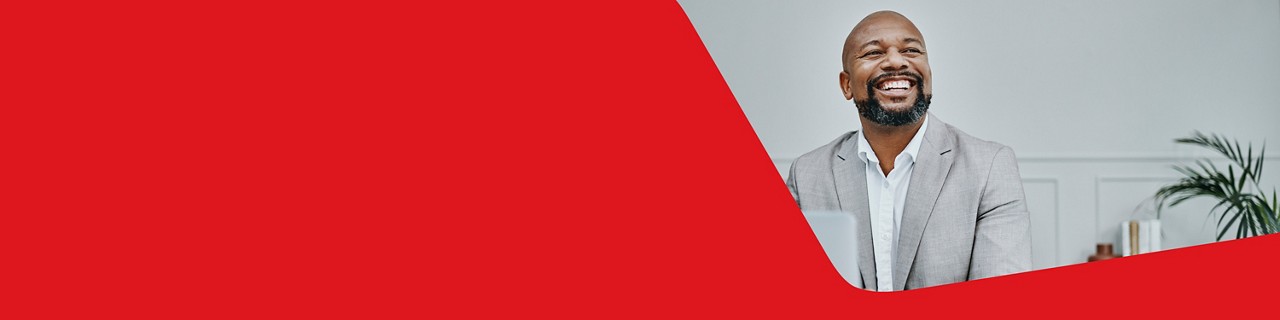 Photo d’un entrepreneur en complet gérant sa carte de crédit Mastercard Entreprise à son ordinateur