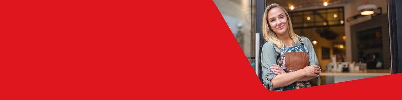 Photo d’une entrepreneure dans l’entrée de son commerce qui sourit grâce aux avantages de la carte de crédit Mastercard Marge Affaires de la Banque Nationale