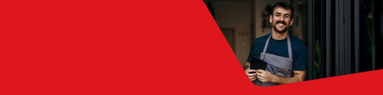 Photo of a restaurant owner in front of their business managing their National Bank Platinum Business Mastercard credit card on their tablet