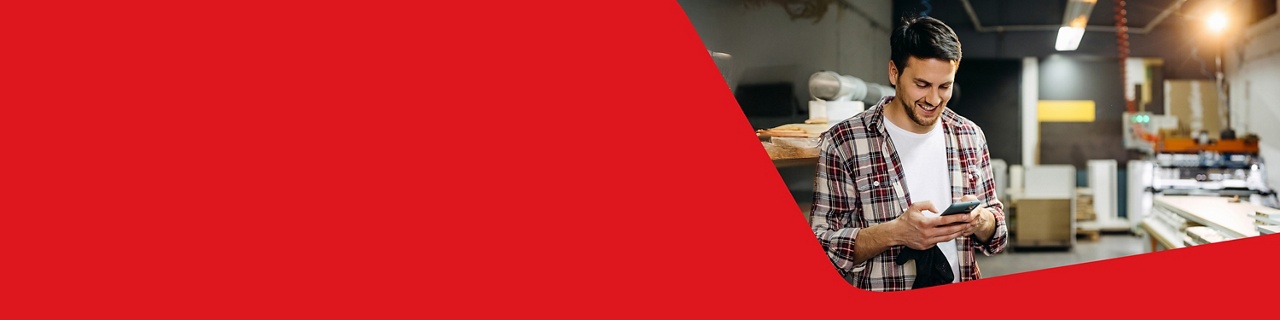 Photo of an entrepreneur in their shop opening an account with the National Bank Digital Business Package on their cell phone