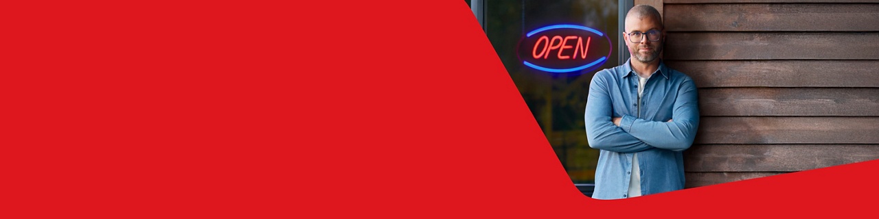 Photo of a business owner in front of their business with an open sign representing National Bank’s business transfer services 