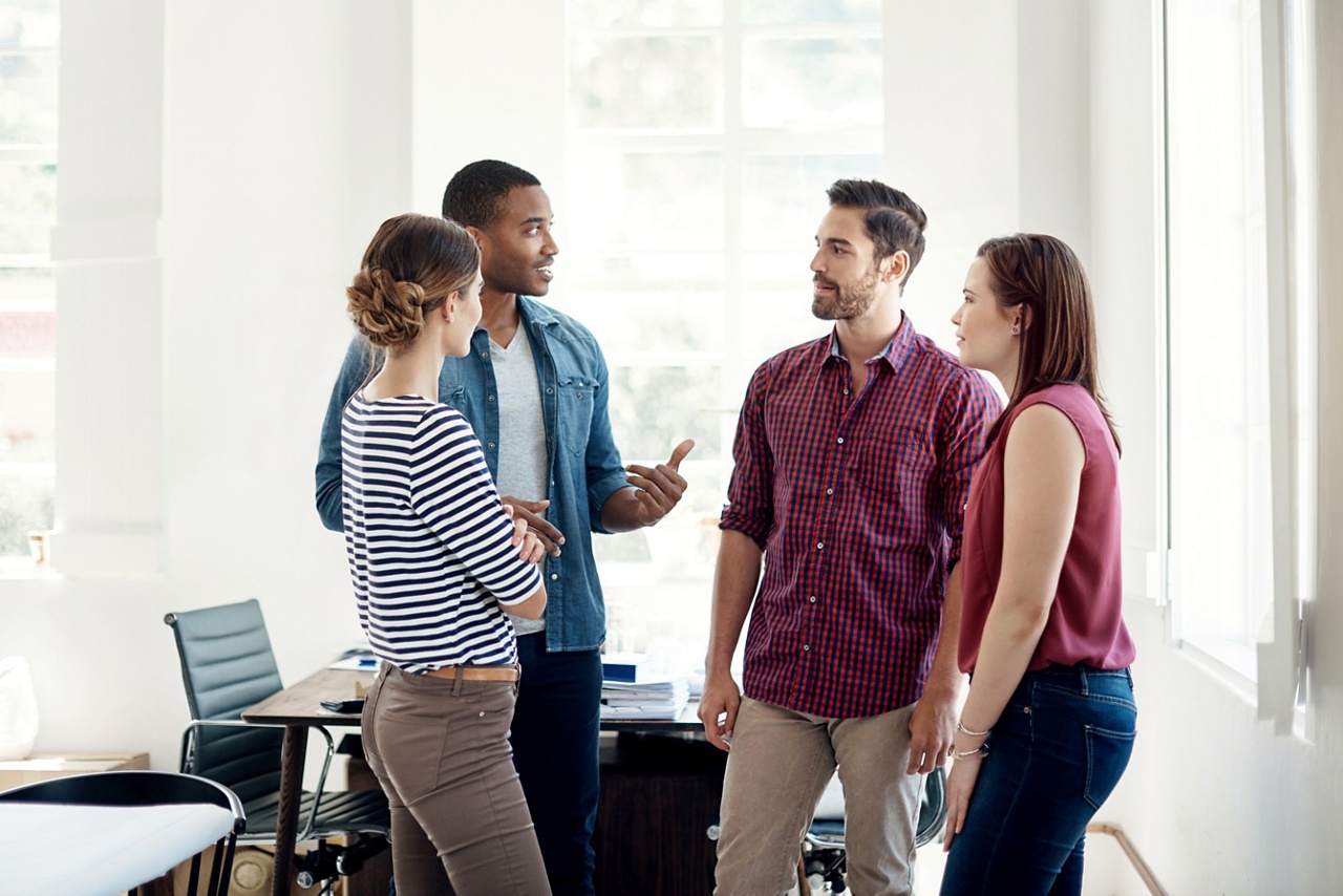 Photo de 4 personnes discutant dans un bureau pour un article sur l’agilité organisationnelle 
