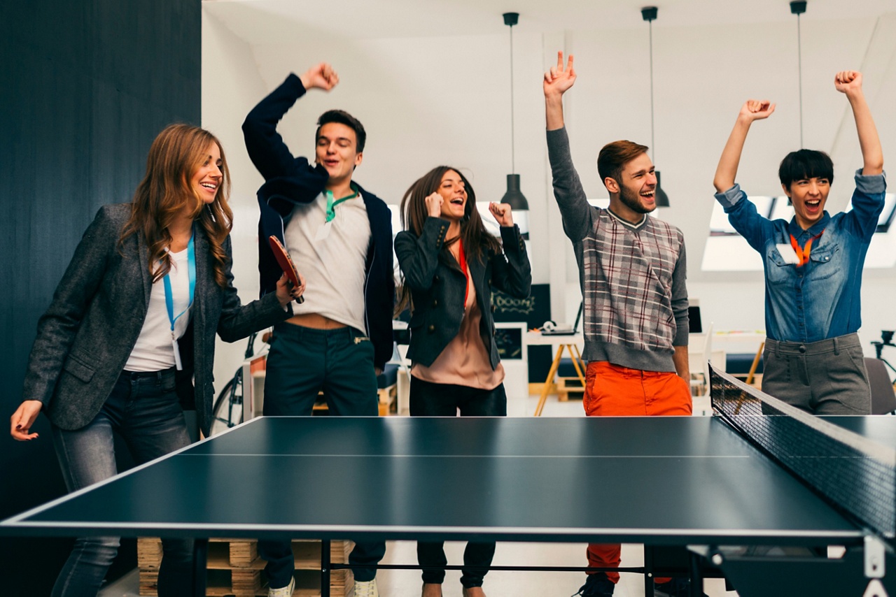 Photo of employees playing ping pong for an article about team building 