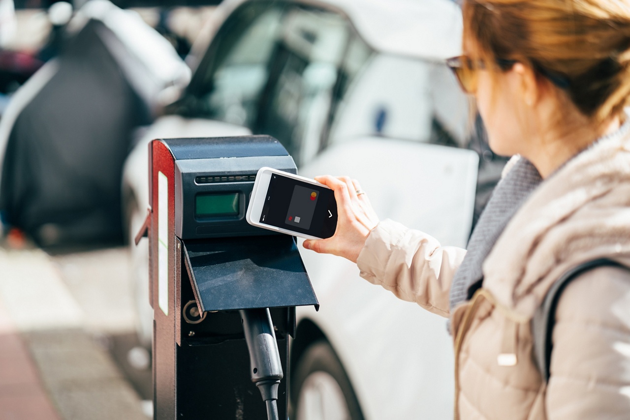 Photo of a person using their phone to pay for an electric car charger for an article about financing innovation